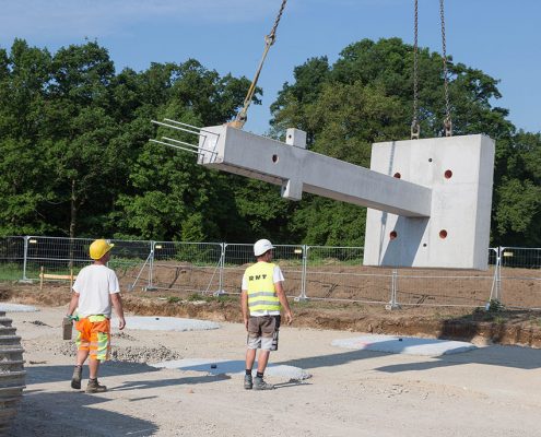 Die schweren Bauteile werden mit Sattelzügen angeliefert und müssen mit einem Kran abgeladen und an der richtigen Position auf der Baustelle platziert werden.